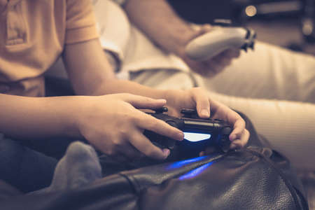 Close-up of son and father playing video games at home.