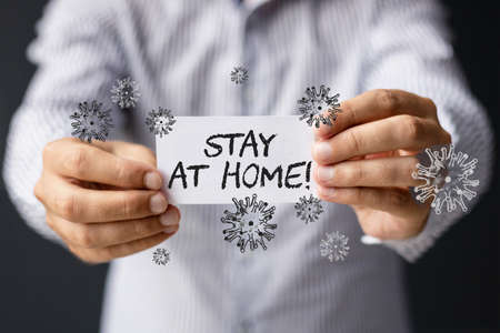 Coronavirus pandemic concept. Close-up of man holding stay at home sign as a warning during virus...