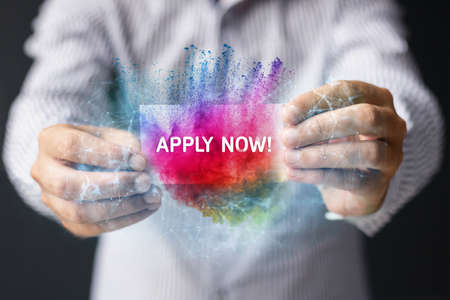 Close-up of person holding apply now business card. Online employment and job search concept.の写真素材