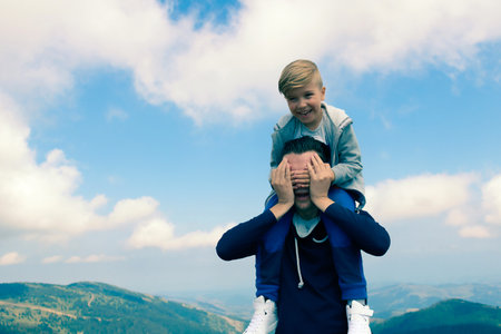 Carefree father and son having fun while spending a day in mountains against the sky.の写真素材