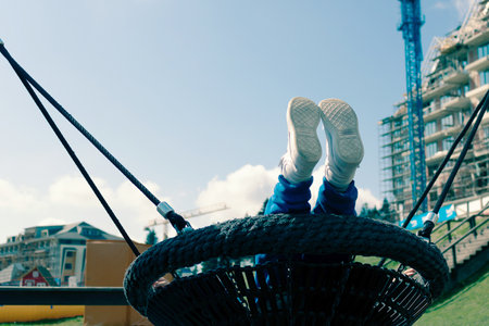 Low angle view of unrecognizable child swinging at the playground.の写真素材