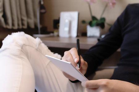 Close-up of unrecognizable man writing notes on the paper.の写真素材
