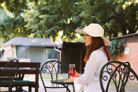 Young redhead woman relaxing at outdoor cafe during summer day.の写真素材