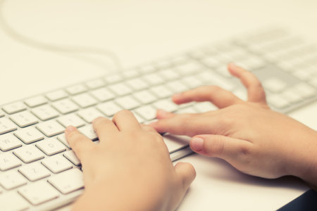Close-up of kid typing on computer keyboard.の写真素材