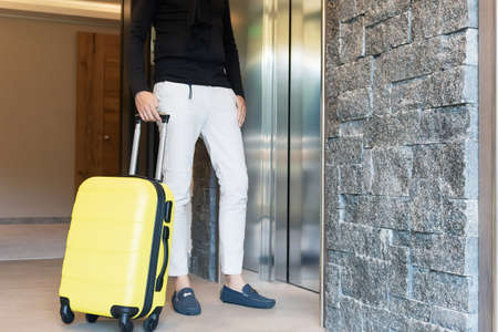 Unrecognizable man with suitcase waiting for the elevator.の写真素材
