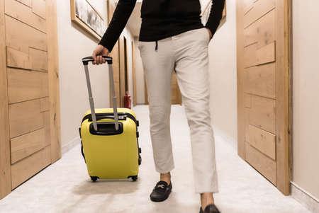 Unrecognizable man with yellow suitcase walking through the lobby.の写真素材