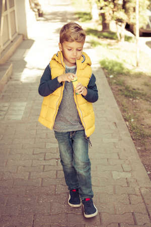 Small kid with bubble wand walking on the street.の写真素材