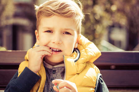 Small boy eating candy while looking at camera.