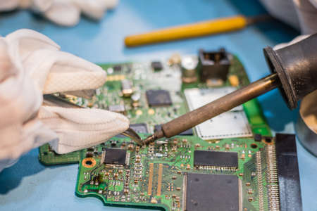 Close up of child soldering computer chip while repairing mother board at IT laboratory.