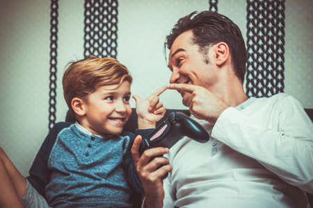 Happy father and son winning in video game and celebrating while pointing at each other.の写真素材