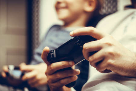 Close-up of parents and child playing video games together.