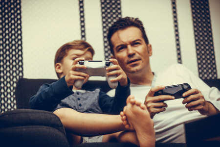 Little boy and his father playing online video games at home.の写真素材