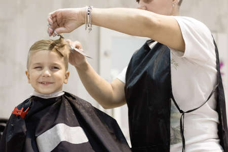 Cute kid making a face while getting haircut at hair salon.の写真素材