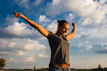 Happy woman with raised arms enjoying in her freedom against the sky.の写真素材