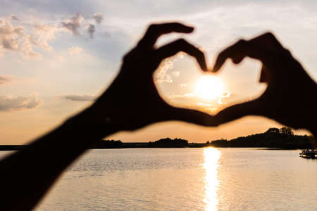 Sunset seen through heart shape at the beach.の写真素材