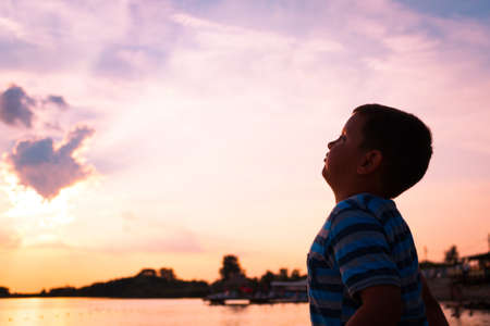 Side view of kid enjoying at beach at sunset. Little boy against the sky.の写真素材
