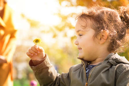 Portrait of happy little girl with dandelion enjoying a day in the park.