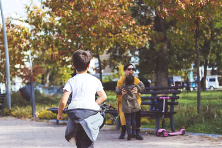 Small boy and girl rushing in mother's arms while meeting with her in the park.の写真素材