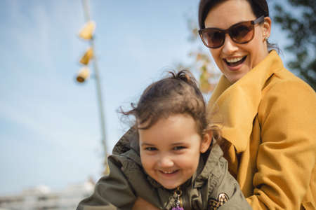 Young happy mother playing with daughter in the city. Joyful mother and daughter having fun together.の写真素材