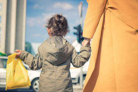 Rear view of daughter holding mother's hand while walking in the city.の写真素材