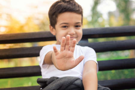 Small boy showing stop sign with his hand while being photographed.の写真素材
