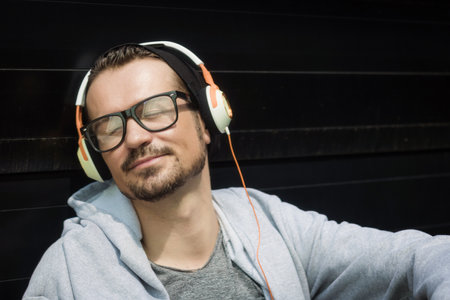 Carefree man listening music over headphones and relaxing with eyes closed.の写真素材