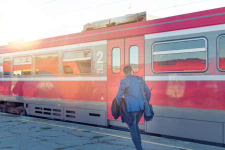 Rear view of businessman running on railroad station and catching the train.の写真素材