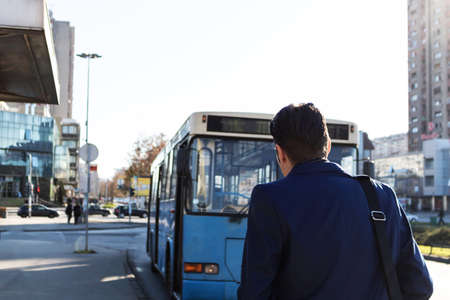 Rear view of man at bus station.の写真素材