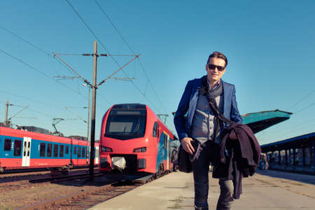 Happy businessman arriving to the city and walking at train station platform.の写真素材