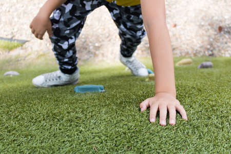 Close-up of kid climbing up on bouldering wall on the playground at the park.