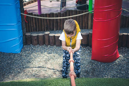 Small kid climbing with a rope while playing on the playground.の写真素材