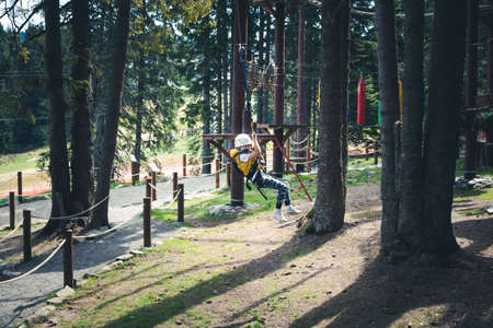 Carefree boy zip lining and having fun after roper course in the forest.の写真素材