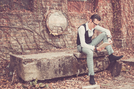 Well dressed man sitting outdoors and reading a book.の写真素材