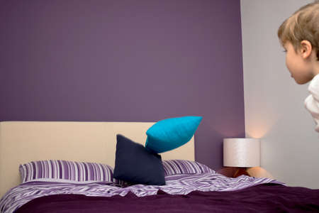 Little boy having fun while throwing pillows on the bed at home.の写真素材