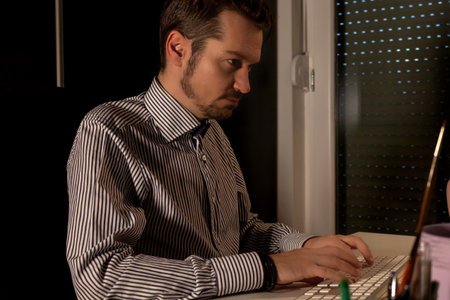 Businessman typing on computer keyboard while working late in the office.