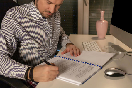 Smiling businessman working late and writing reports in the office.