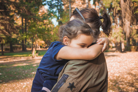 Sad little girl embracing her mother while spending a day in the park.の写真素材
