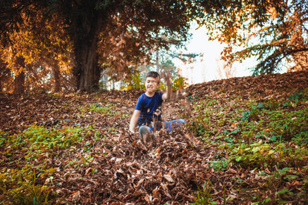 Carefree kid throwing autumn leaves in the air while playing in the forest.の写真素材