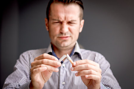 Close-up of man quitting smoking and breaking cigarette in half. Stop smoking concept.の写真素材