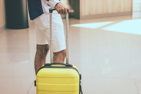 Unrecognizable person with travel bag standing in hotel hallway.の写真素材
