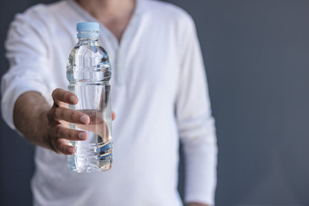 Man holding and offering bottle of fresh water. The importance of hydration.