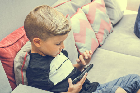 Small kid playing video games on portable device.の写真素材