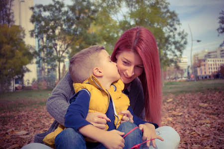 Affectionate son kissing his mother while enjoying in time together at the park.の写真素材