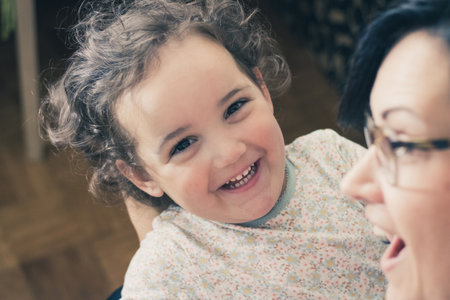 Cute little girl having fun with her mother and laughing while looking at camera.の写真素材