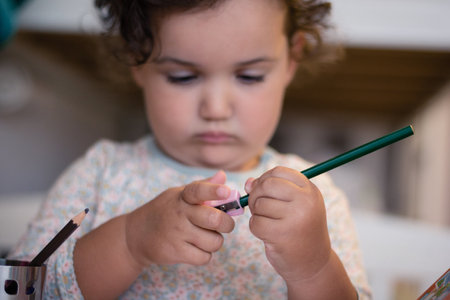 Close up of little girl sharpening green crayon. Close up of child using pencil sharpener.の写真素材