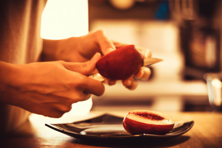 Close-up of woman slicing peach in the kitchen.の写真素材