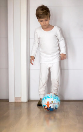 Small kid having fun while playing with ball in a hallway.の写真素材