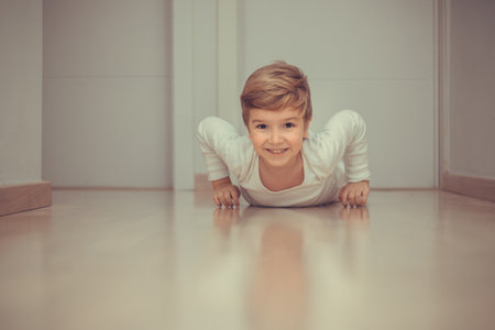Playful kid having fun while crawling on parquet floor at home.の写真素材