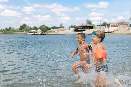 Playful kid splashing water while running through sea and having fun in summer day.の写真素材