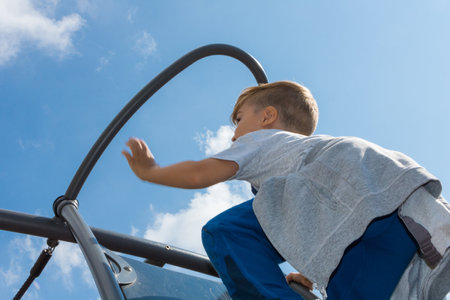 Low angle view of kid climbing up on monkey bars at the playground.